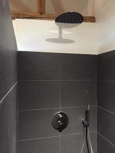 a bathroom with a shower with a black tiled wall at Le Vieux Logis de la Galocherie in Sainte-Florence
