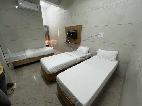 a room with two beds and a tv in it at Vrajvashi-Home Stay in Dwarka