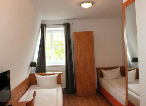 a small room with two beds and a window at Hotel Waitzingers in Landsberg am Lech