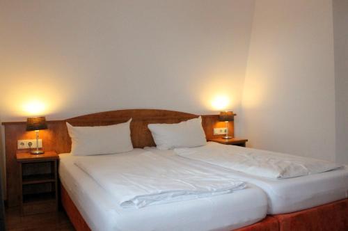 a bedroom with a bed with two lamps on two tables at Hotel Waitzingers in Landsberg am Lech