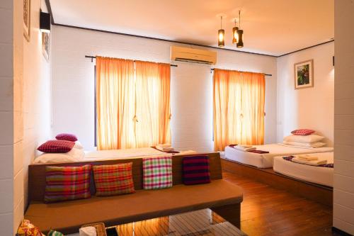 a room with two beds and a bench in it at Thanicha Resort Amphawa in Amphawa