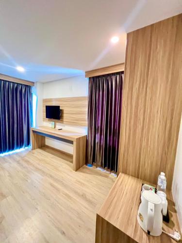 a room with a desk and a tv and curtains at เวลโกรว์ โฮเทล - Wellgrow Hotel in Ban Bang Kha