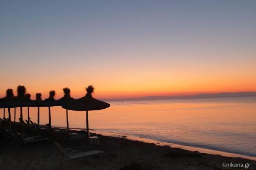 a group of people sitting under umbrellas on the beach at sunset at Diana's Penthouse in Perea