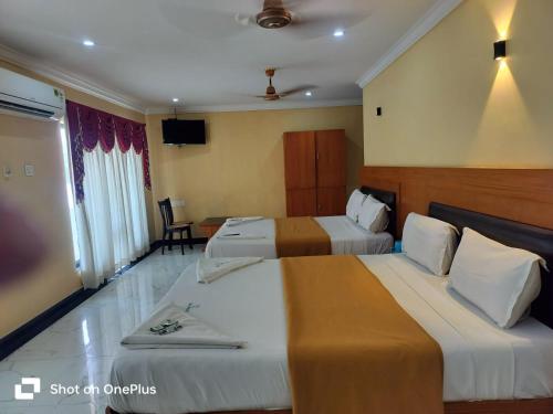 a hotel room with two beds and a television at Hotel Sun World in Kanyakumari