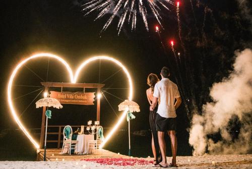 a man and a woman standing on the beach with fireworks at Vila Ombak in Gili Trawangan