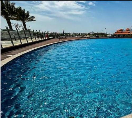 a large pool of blue water next to a sidewalk at Fleur Star Apartments in Dubai