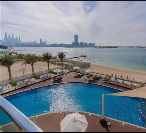 a swimming pool next to a beach and the ocean at Fleur Star Apartments in Dubai