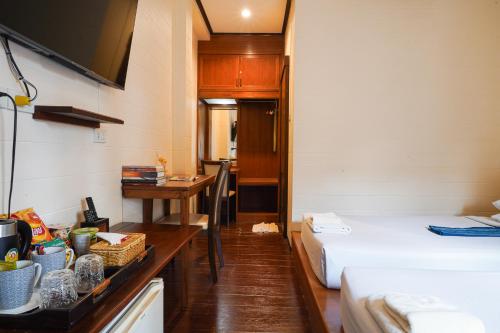 a room with two beds and a desk and a table at Thanicha Resort Amphawa in Amphawa