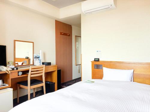 a bedroom with a bed and a desk with a computer at Hotel Route-Inn Nagaizumi Numazu Inter 1 in Nagaizumi