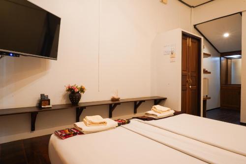 a room with two beds and a tv on the wall at Thanicha Resort Amphawa in Amphawa