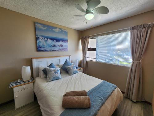a bedroom with a bed with a ceiling fan and a window at Beautiful Sea view apartment 45 De Valle Diaz Mosselbay in Mossel Bay
