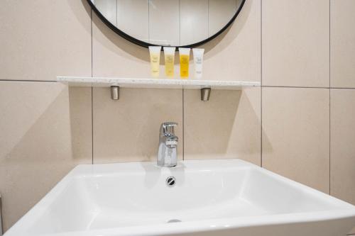 a bathroom sink with a mirror on the wall at DongBaek Hotel Gohyeon in Geoje 