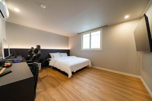 a bedroom with a bed and a desk and a window at DongBaek Hotel Gohyeon in Geoje 