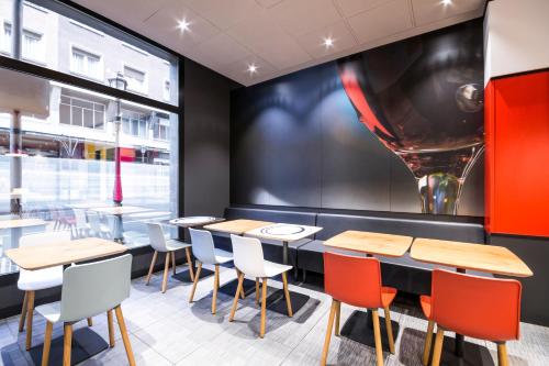 a restaurant with tables and chairs and a large window at Ibis Bilbao Centro in Bilbao