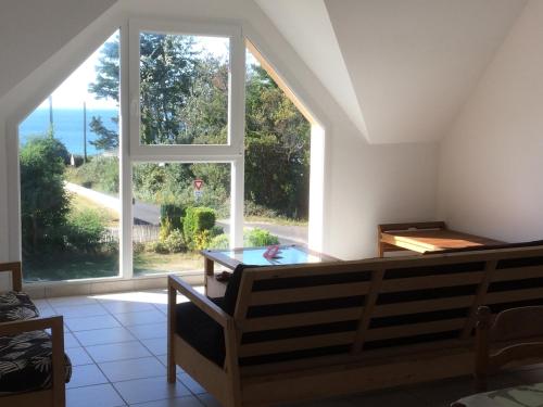 un salon avec une grande fenêtre et une table dans l'établissement Maison Trez Rouz, à 100m de la plage , vue mer, à Crozon