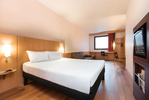 a hotel room with a large white bed and a tv at Ibis Bilbao Centro in Bilbao