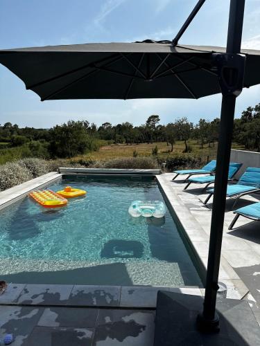 une piscine avec un parasol et des structures gonflables dans l'établissement villa a calata, à Porto-Vecchio