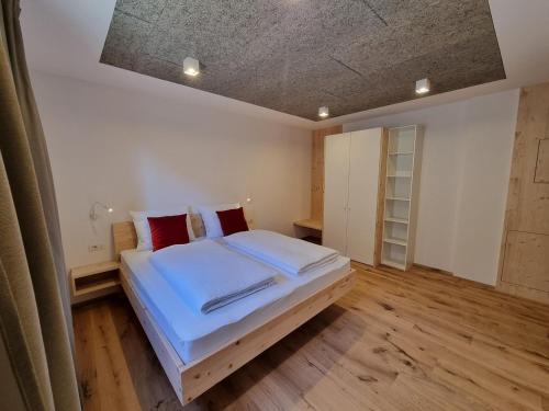 a bedroom with a bed with white sheets and red pillows at Laimbruchhof Apartments Urlaub auf dem Bauernhof in Val di Vizze