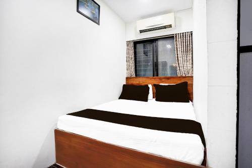 a bedroom with a bed with white sheets and black pillows at Super Hotel O BKC Santacruz East in Mumbai