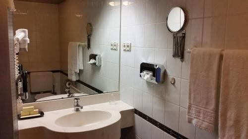 W łazience znajduje się umywalka, lustro i ręczniki. w obiekcie Eppelborner Hof w mieście Eppelborn