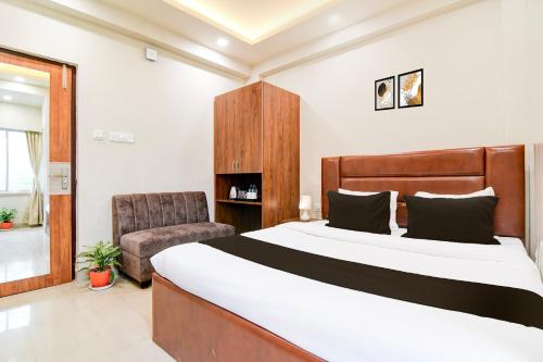 a bedroom with a large bed and a chair at Super Townhouse Kaikhali Near Airport in Kolkata