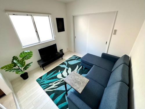 a living room with a blue couch and a tv at キーサイド桜木町301 in Yokohama