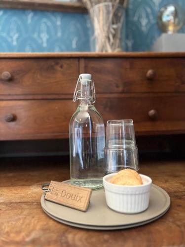 une bouteille en verre sur une assiette avec un bol de pain dans l'établissement Le Presbytère de Darcey, à Darcey