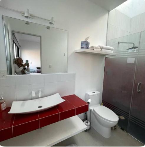 a person taking a picture of a bathroom with a red sink at Casa del Unicornio Azul in Cocoyoc