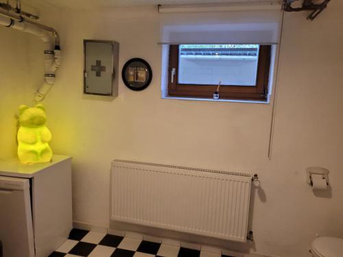 a bathroom with a yellow teddy bear sitting on a toilet at Monteurzimmer in Pfreimd