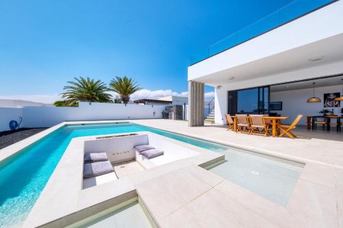 a villa with a swimming pool and a dining area at White House - Fire pit and Private pool By Lanzarote Vacation Homes in Puerto Calero