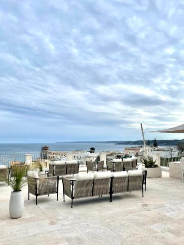 a group of chairs and tables on a patio with the beach at Est hotel in Santa Cesarea Terme