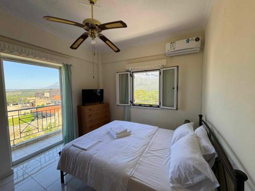 a bedroom with a bed with a ceiling fan and a window at Santis apartment in Areopolis