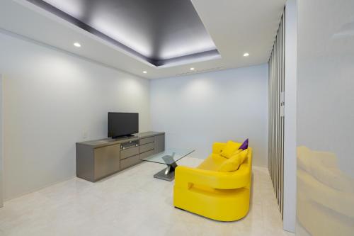 a yellow chair in a living room with a tv at Namari Onsen Kokoro No Toki Jusangatsu in Hanamaki
