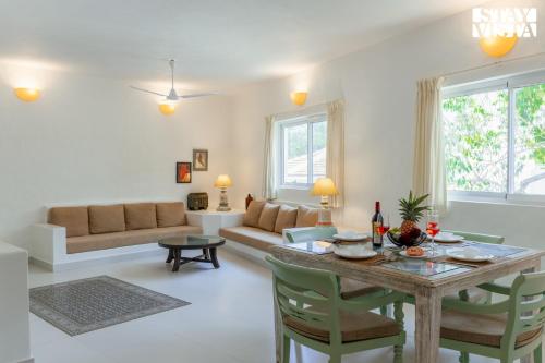 a living room with a table and a couch at StayVista at Suite De Regal in Mandrem