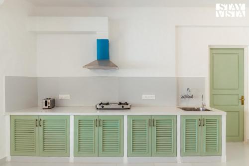 Una cocina con gabinetes verdes y un fregadero. en StayVista at Suite De Regal, en Mandrem