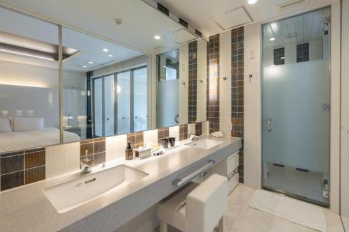 a bathroom with a sink and a large mirror at Namari Onsen Kokoro No Toki Jusangatsu in Hanamaki
