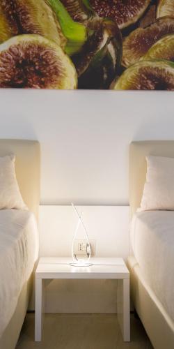 a table between two beds with a painting on the wall at Est hotel in Santa Cesarea Terme