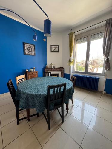 une salle à manger avec une table et un mur bleu dans l'établissement Colorful 1930s house, à Portes-lès-Valence