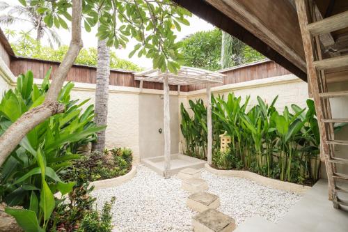 a courtyard with an umbrella and some plants at Vila Ombak in Gili Trawangan