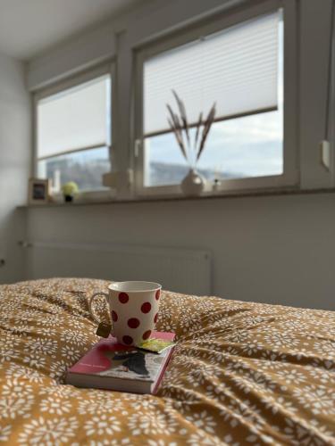 a coffee cup sitting on top of a bed at Ferienwohnung Opas Gewächshaus in Bad Laasphe