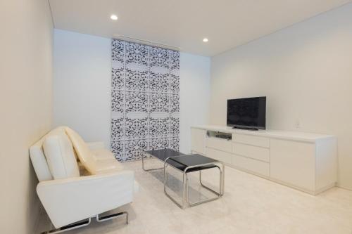 a white living room with a chair and a television at Namari Onsen Kokoro No Toki Jusangatsu in Hanamaki