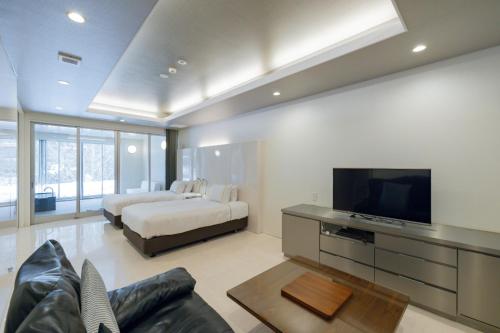 a living room with a bed and a television at Namari Onsen Kokoro No Toki Jusangatsu in Hanamaki