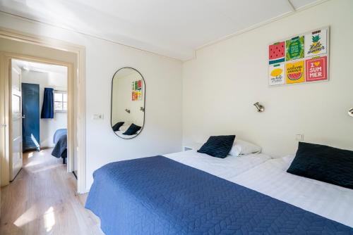 a bedroom with a blue and white bed and a mirror at Duinhotel Haga in Zoutelande