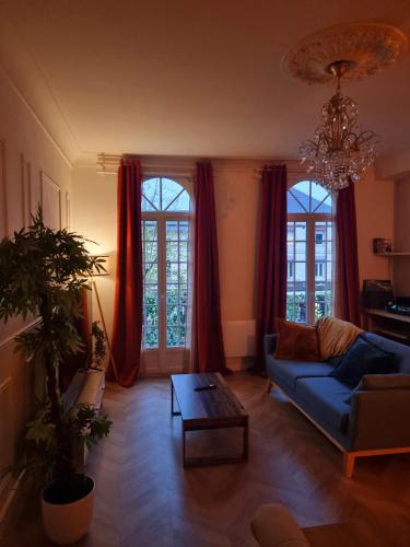 - un salon avec un canapé bleu et des rideaux rouges dans l'établissement Le Classique, à Montpon-Ménestérol