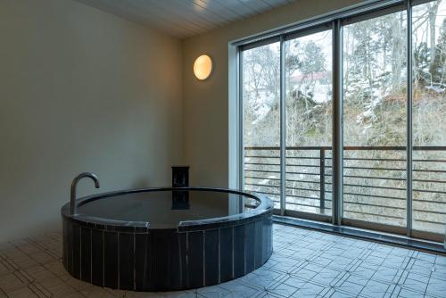 a large wooden tub in a room with large windows at Namari Onsen Kokoro No Toki Jusangatsu in Hanamaki