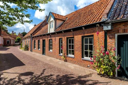 a brick building with a red roof on a street at Winsum - Groningen - 6 pers. Cosy Cottage - Op en Bie t Woater in Winsum