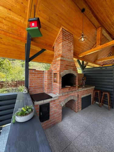a brick oven in a patio with a wooden roof at Casa din Vale apartament - Valiug in Văliug