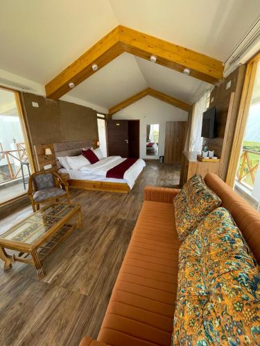 a bedroom with a bed and a couch in a room at Maatidera Resort Kanatal The Boutique stay in the Lap of Himalayas in Kanatal