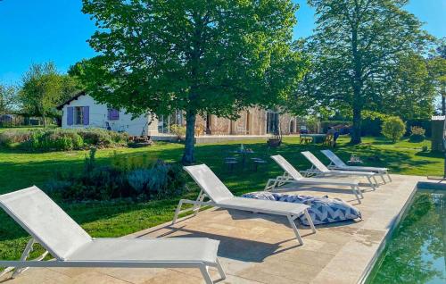 a row of lounge chairs sitting next to a pool at Nice Home In Saint-Géraud-De-Corps in Saint-Géraud-de-Corps