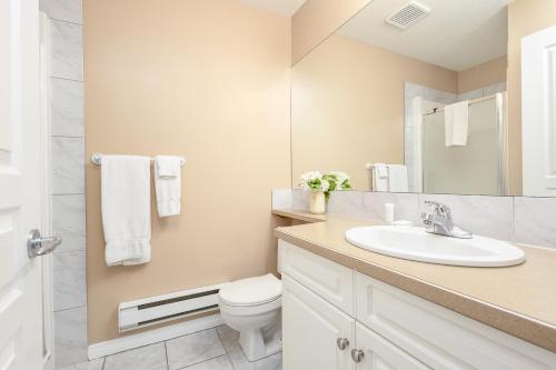une salle de bain avec un lavabo, des toilettes et un miroir dans l'établissement Paradise Canyon Golf Resort - Luxury Condo M409, à Lethbridge